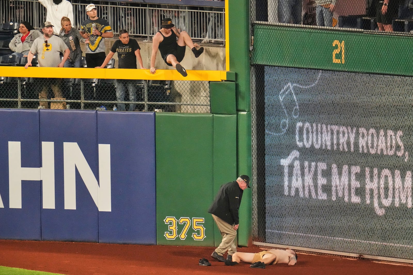 A fan lies on the warning track in right field of PNC Park after falling out of the stands during the seventh inning of a baseball game between the Pittsburgh Pirates and the Chicago Cubs in Pittsburgh, Wednesday, April 30, 2025. (AP Photo/Gene J. Puskar)