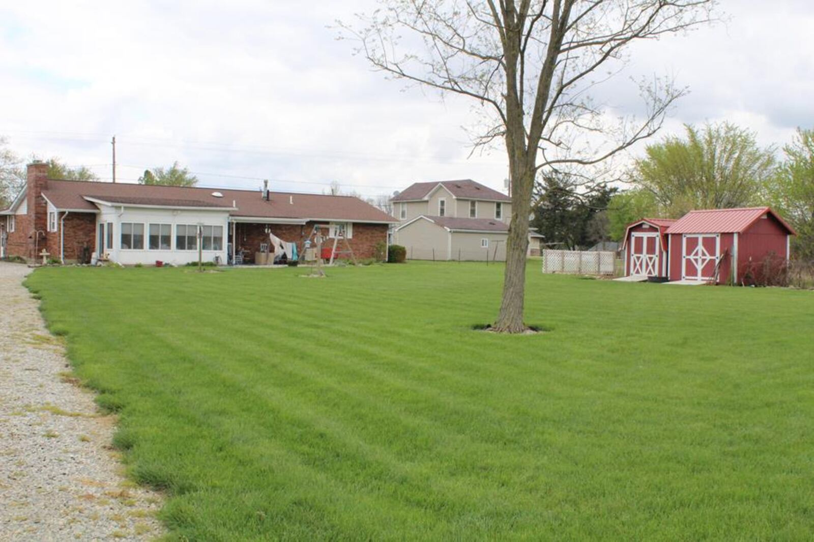 The rear of the home has a sunroom connected to a covered concrete patio. The yard is fully fenced and has two yard barns, a horse barn and pasture.