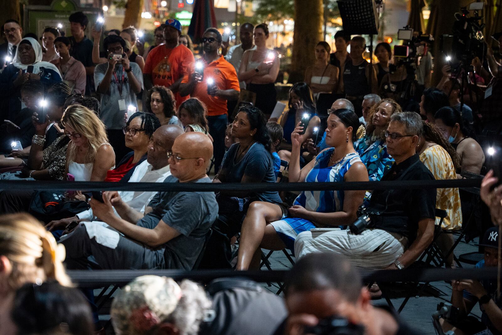 People raise their phone lights during the vigil for the victims killed in the previous day's shooting at 345 Park Avenue, including NYPD officer Didarul Islam, in Bryant Park, Tuesday, July 29, 2025, in New York. (AP Photo/Angelina Katsanis)