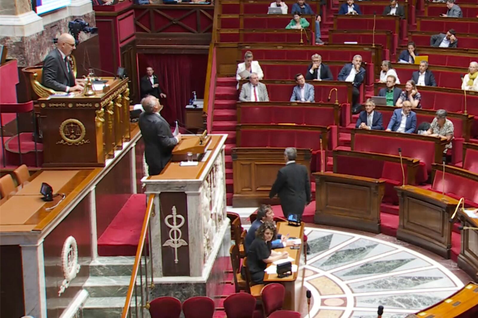 This video image provided Thursday June 26, 2025 by the National Assembly shows the assembly vice president, Roland Lescure, left, and Prime Minister Francois Bayrou, center, looking up as the domed ceiling leaks during torrential storms in Paris, Wednesday, June 25, 2025. (Assemblée Nationale via AP)