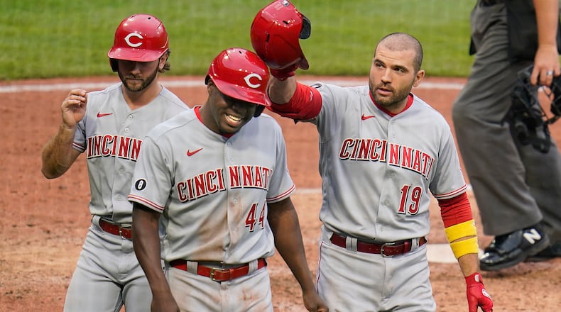 Cincinnati Reds' Joey Votto (19) celebrates with Aristides Aquino (44) and Max Schrock all three scored on Votto's three-run home run off Pittsburgh Pirates starting pitcher Cody Ponce (44) during the fifth inning of a baseball game in Pittsburgh, Sunday, Oct. 3, 2021. (AP Photo/Gene J. Puskar)