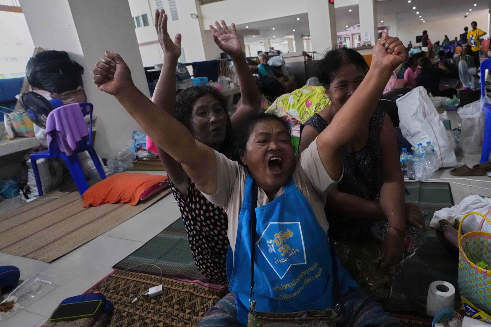 Thai residents who fled homes following the clashes between Thai and Cambodian soldiers, celebrate at an evacuation center in Surin province, Thailand, Monday, July 28, 2025 after hearing Immediate and unconditional cease fire with effect from 24 hours local time, midnight on 28 July 2025. (AP Photo/Sakchai Lalit)
