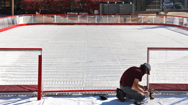 The new ice skating rink being constructed on the Springfield City Hall Plaza glows in the early morning sunlight as a worker erects the transparent wall around the outside Thursday, Nov. 3, 2022. Precision Ice Rinks, is the company building the ice rink that will be open on November 25 for the Holiday in the City celebration and continue through New Year's. BILL LACKEY/STAFF