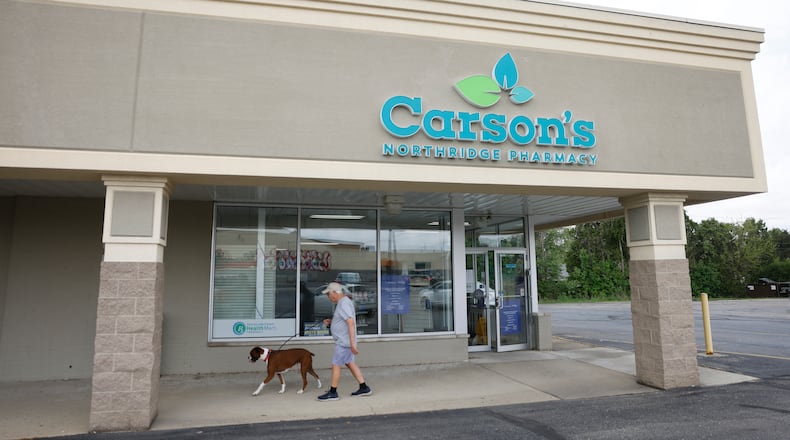 John Barker walks with Jax, his 3-year-old boxer, on Friday, May 2, 2025, at Carson's Northridge Pharmacy. The drug store is closing next week. JOSEPH COOKE/STAFF