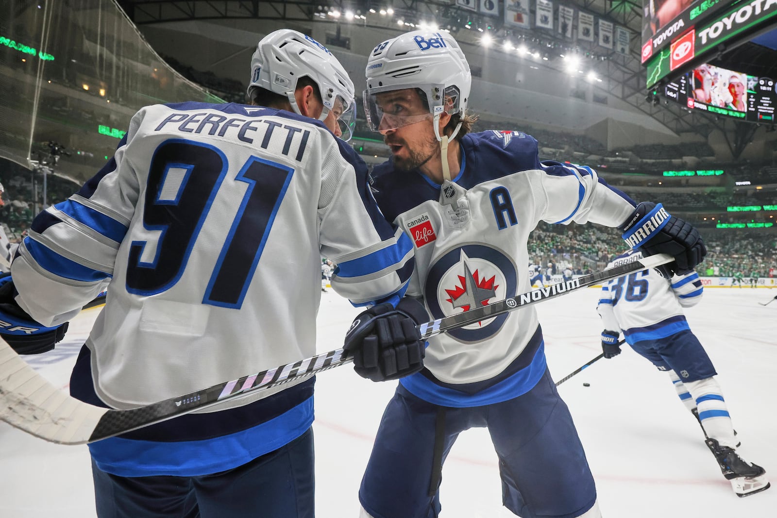 Winnipeg Jets' Cole Perfetti (91) and Mark Scheifele, right, talk during warmups before first Game 6 of a second-round NHL hockey playoff series against the Dallas Stars in Dallas, Saturday, May 17, 2025. (AP Photo/Gareth Patterson)