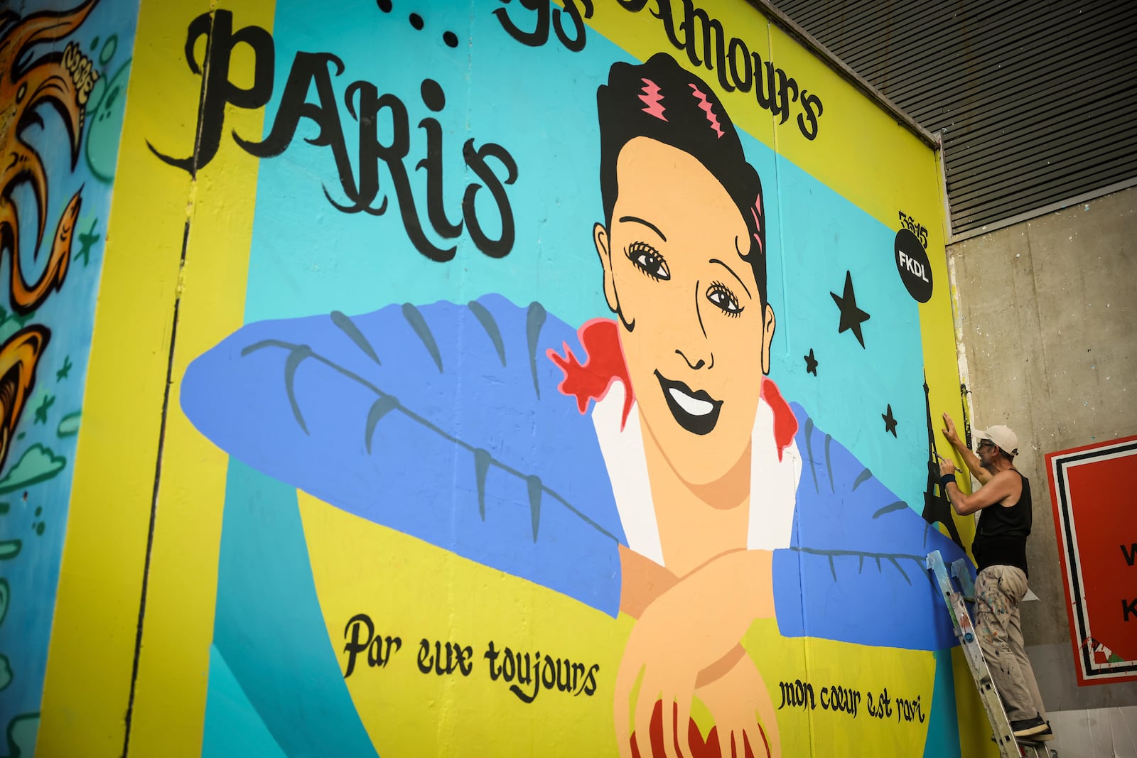 Artist Franck Duval, aka FKDL, works on a mural of U.S.-French entertainer and civil rights activist Josephine Baker in Paris, Saturday, July 19, 2025. (AP Photo/Thomas Padilla)