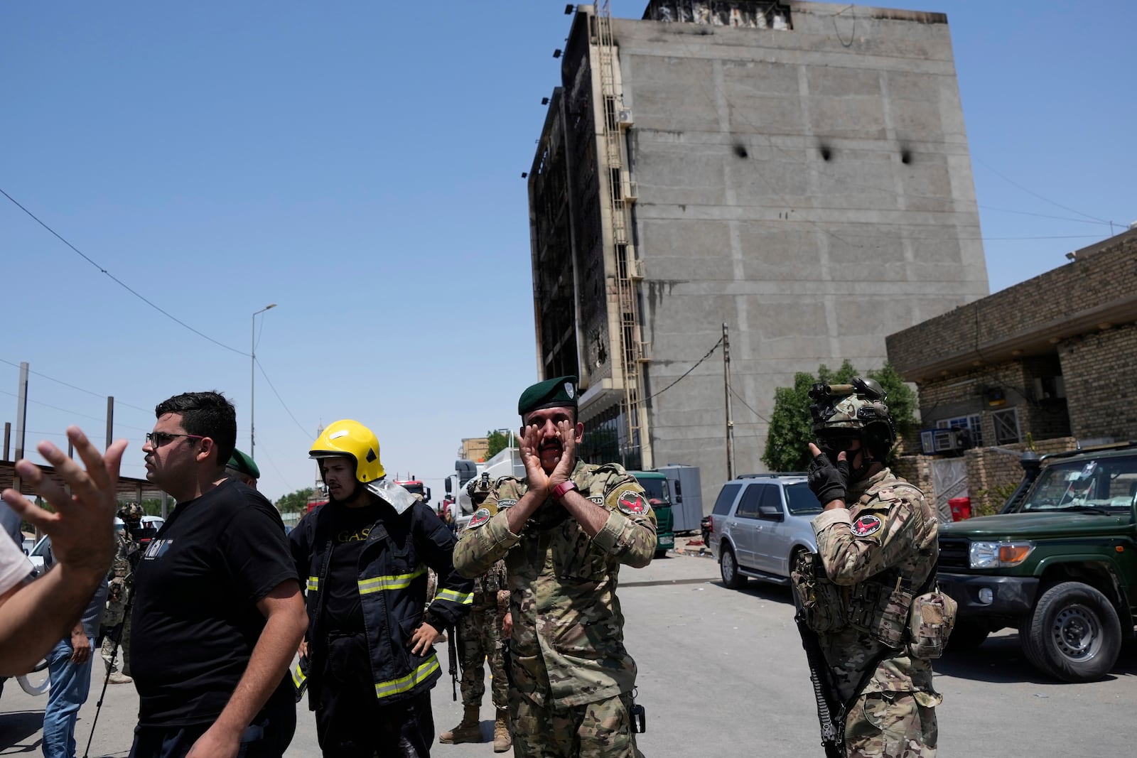 Iraqi Security forces gather in front of a burning hypermarket building in Kut, Iraq, Thursday, July 17, 2025. (AP Photo/ Hadi Mizban)