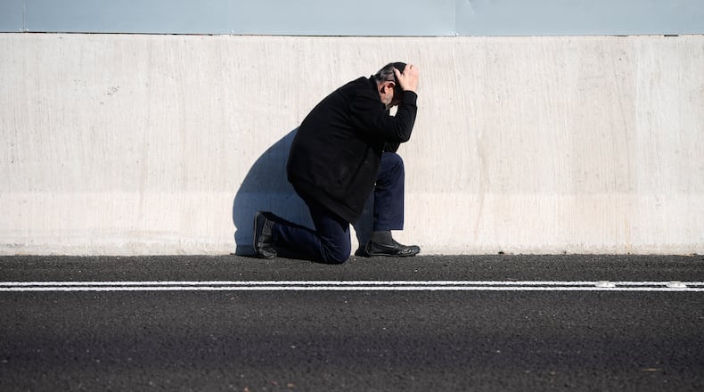 A man takes cover by the side of the road as an air raid sirens warn of incoming Iranian missile strikes in Tel Aviv, Israel, March 17, 2026. (AP Photo/Ohad Zwigenberg)