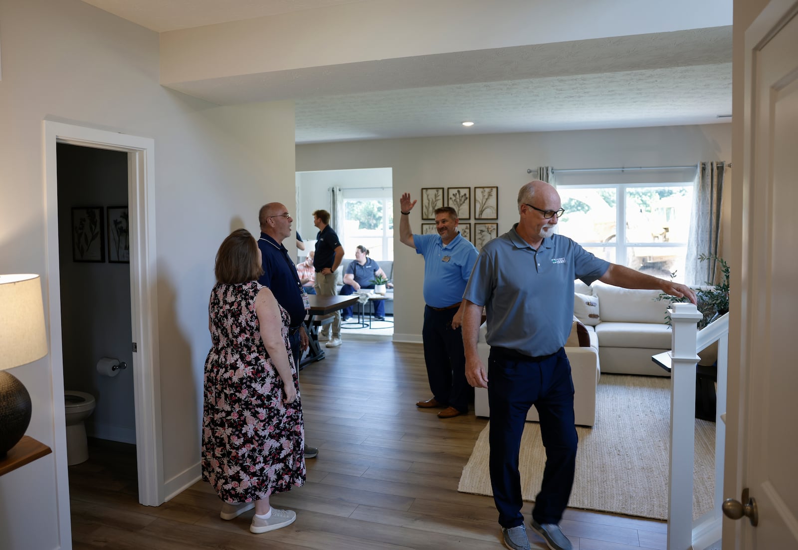 Kevin Baechle, center, regional sales manager of Arbor Homes, socializes as Andy Glassmeyer, right, land acquisition manager of Arbor Homes, prepares to see the upstairs area of a home during the grand opening of Monroe Meadows housing development on Friday, June 27, 2025, in New Carlisle. JOSEPH COOKE/STAFF

