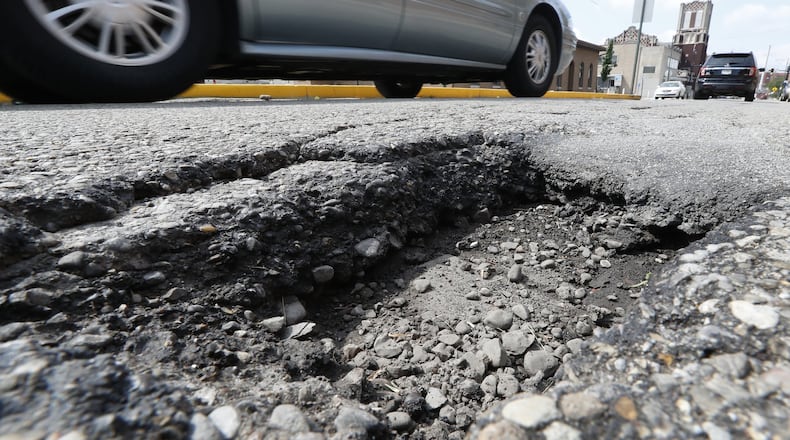Cars drive around a pothole, several inches deep, along Center Street between Pleasant Street and North Street Friday. Bill Lackey/Staff