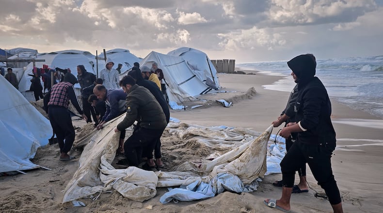 Palestinians try to recover their tent after overnight rainfall flooded their beachside tent camp in Khan Younis, in the southern Gaza Strip, Sunday, Dec. 28, 2025. (AP Photo/Mohammad Jahjouh)