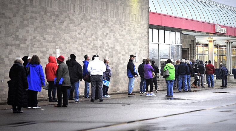 People wait outside Meijer in Springfield Monday morning. MARSHALL GORBY/STAFF