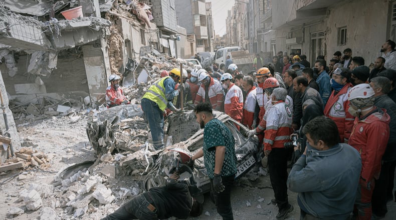 First responders inspect a destroyed car at the site of a residential building hit in an overnight strike during the U.S.-Israeli military campaign in Tabriz, East Azerbaijan Province, northwestern Iran, Tuesday, March 24, 2026. (AP Photo/Matin Hashemi)