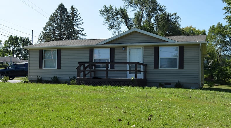 The front of this 3-bedroom home with about 1,040 sq. ft. of living space features a wood deck with railing. There is a large asphalt driveway connected to a concrete walk leading to the front. CONTRIBUTED PHOTO
