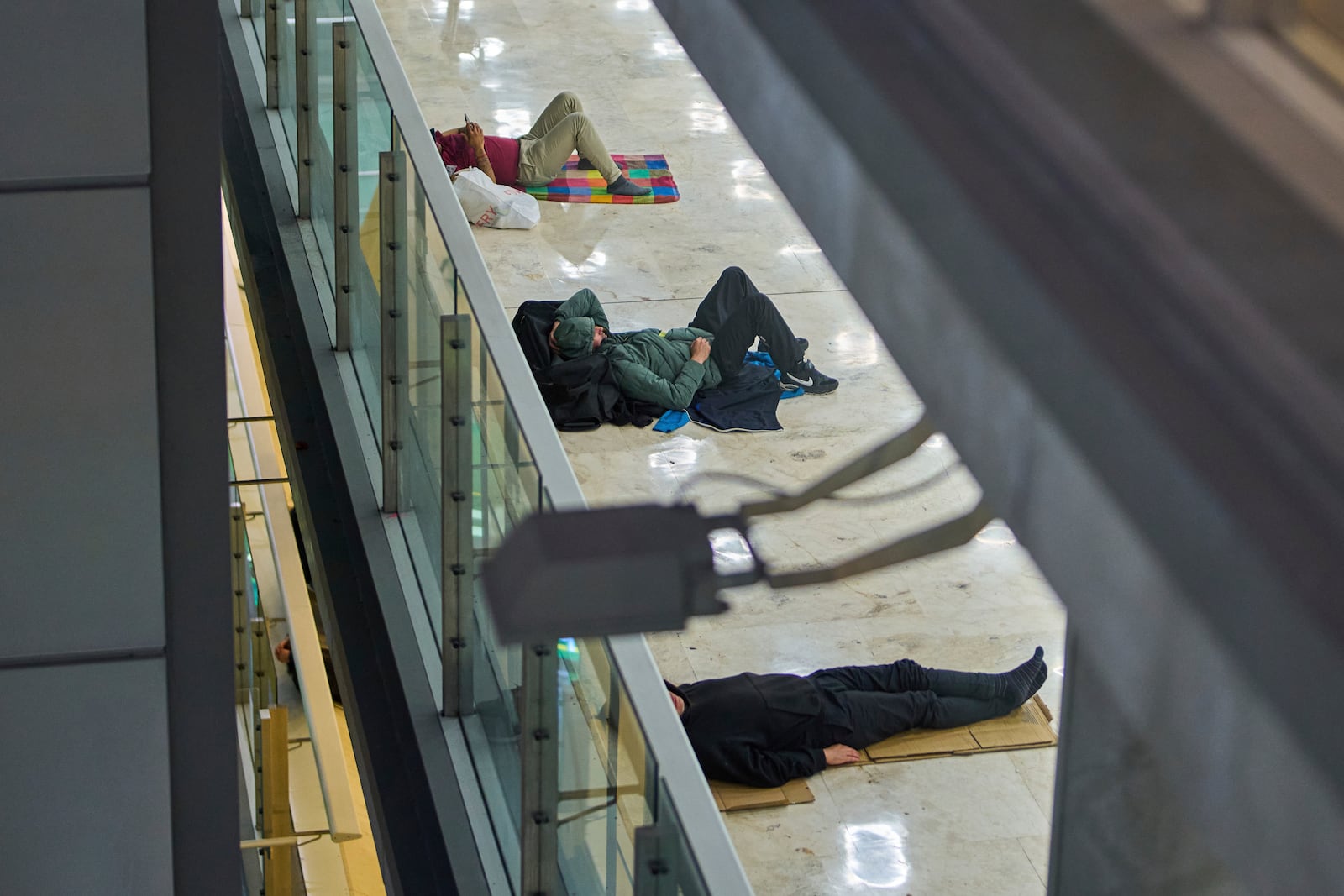 People sleep on the floor of Terminal 4 at Adolfo Suarez-Madrid Barajas Airport in Madrid, Spain, Thursday, May 15, 2025. (AP Photo/Manu Fernandez)
