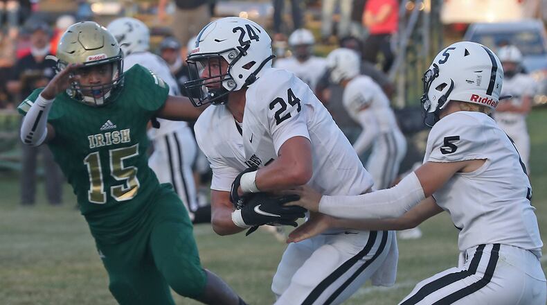Greenon quarterback Evan Davis hands the ball off the Trevor Stewart as Catholic Central's Jaylen Phillips tries to catch him. BILL LACKEY/STAFF