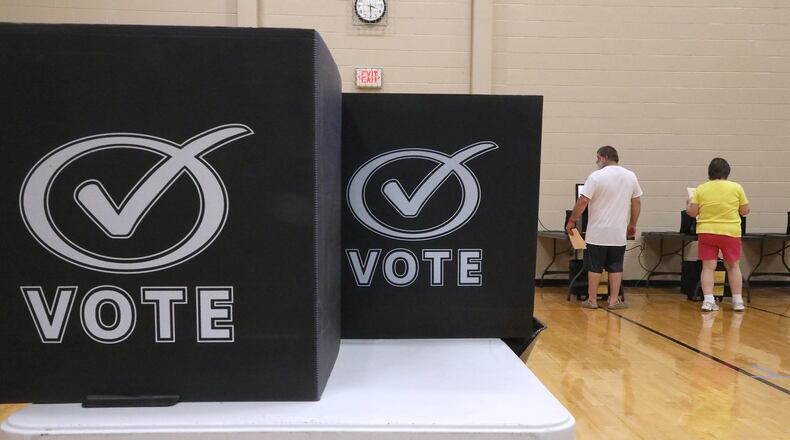 Voters place their ballots in the voting machines at the New Carlisle election poll in Tecumseh High School. BILL LACKEY/STAFF