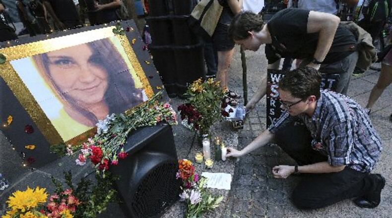 Stephen Friedrich, front, and Scott Douglas set out candles for Heather Heyer as hundreds gather at Woodruff Park on Sunday, Aug. 13, 2017, in Atlanta. Protesters decrying hatred and racism converged around the country on Sunday, saying they felt compelled to counteract the white supremacist rally that spiraled into deadly violence in Virginia. (Curtis Compton/Atlanta Journal-Constitution via AP)