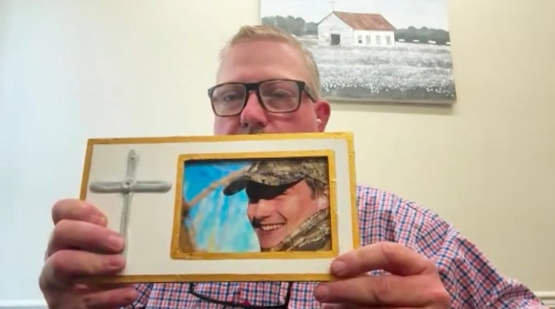 This image taken from video shows Brian Montgomery holding a photo of his son Walker Montgomery while being interviewed by The Associated Press on Wednesday, March 25, 2026, Starkville, Miss. (AP Photo)