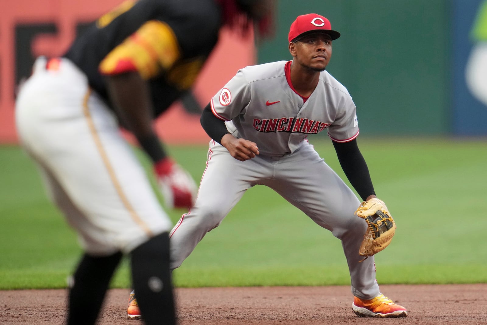 Cincinnati Reds' Ke'Bryan Hayes, right, gets set for a pitch as Pittsburgh Pirates' Oneil Cruz, left, leads off third base during the first inning of a baseball game in Pittsburgh, Thursday, Aug. 7, 2025. (AP Photo/Gene J. Puskar)