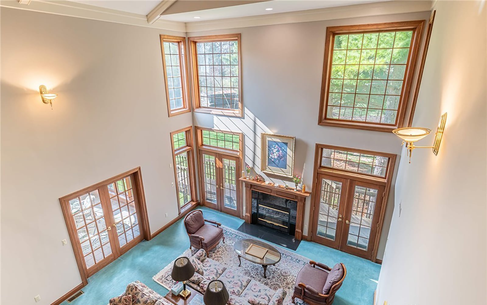The two story great room has a gas fireplace and a beamed ceiling with a ceiling fan. There are two sets of french doors flanking the fireplace opening to the wood deck at the rear of the home.