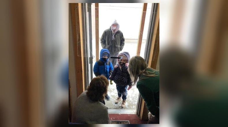 Tosha Moore, center, and kids Landon, left, and Rae'Lyn are greeted by volunteers Charlene Nunley and AnnaMarie Day at the Springfield Soup Kitchen on Christmas Day. The family received a hot meal to go and the kids got gifts. There were 86 people served in two hours. Photo by Brett Turner