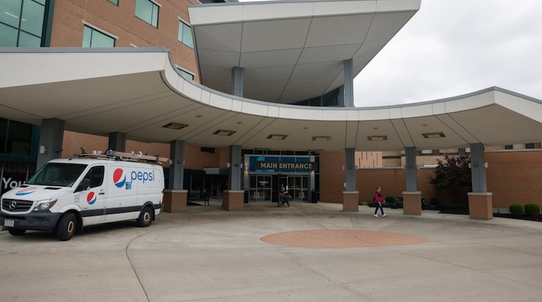 A doctor and patient exit from the main entrance of Kettering Health Dayton on Thursday, May 22, 2025. JOSEPH COOKE/STAFF
