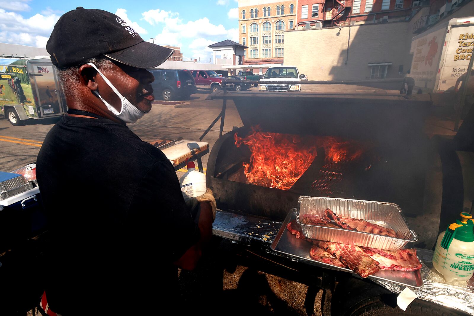 Walter Reeder turns away from the smoke as he waits for his cooker to heat up at the Riddles Texas Cowby BBQ booth at National Road Commons Park for the third annual Springfield Jazz & Blues Fest Friday, August 9, 2024. The musical event, at the Commons park and Mother Stewart's Brewing Co., is presented by the Springfield Kiwanis and features 18 acts featuring national, regional and local performers. The event will continue through Saturday evening. BILL LACKEY/STAFF