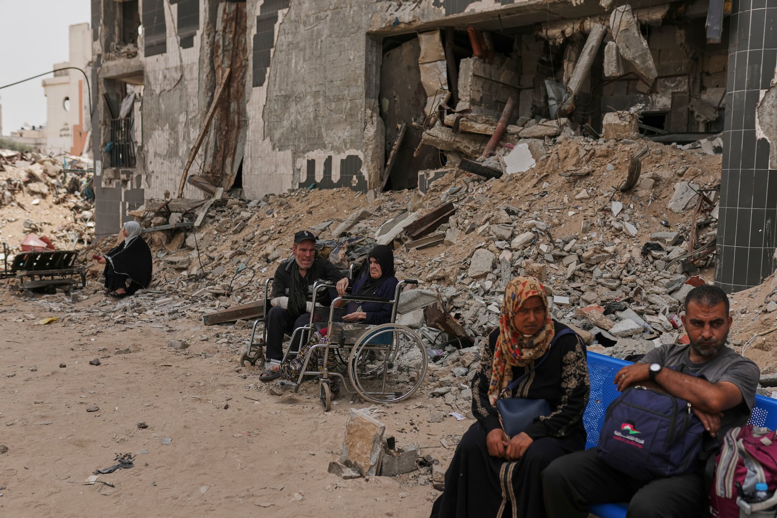 Kidney patients sit amid the destruction caused by the Israeli army at Shifa Hospital compound in Gaza City on Tuesday, July 1, 2025, as they wait to leave after the facility suspended its dialysis unit services due to fuel shortages needed to power its generators. (AP Photo/Jehad Alshrafi)
