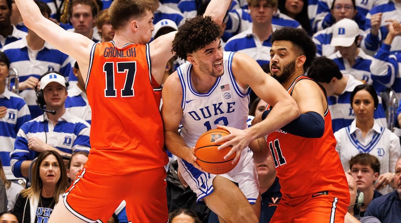 Duke's Cameron Boozer (12) handles the ball between Virginia's Johann Grünloh (17) and Devin Tillis (11) during the first half of an NCAA college basketball game in Durham, N.C., Saturday, Feb. 28, 2026. (AP Photo/Ben McKeown)