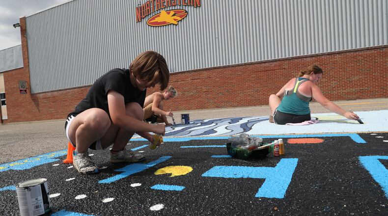 Northeastern incoming seniors, from left, Arianne Potts, JT Hall and Valerie Locke paint their assigned parking places in the school parking lot Wednesday. Students are returning to school as medical officials continue to weigh the impact of the coronavirus on children. BILL LACKEY/STAFF