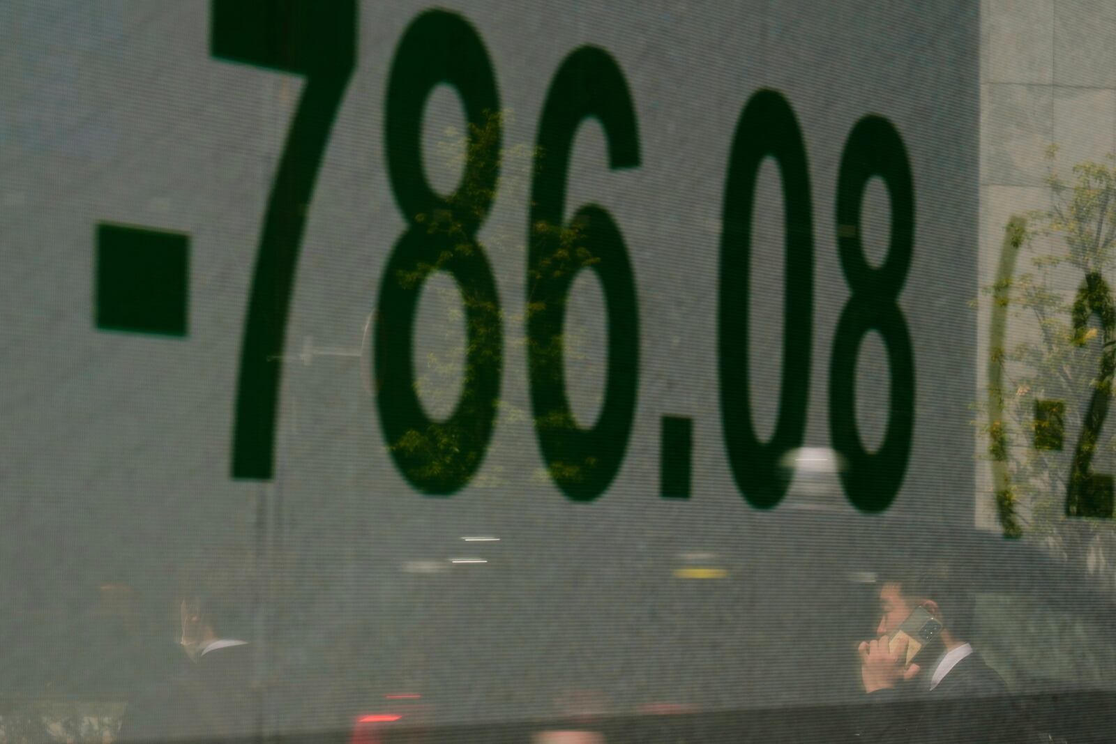 A man talking on the phone is reflected on a screen showing Japan's Nikkei 225 index at a securities firm in Tokyo, Wednesday, April 9, 2025. (AP Photo/Hiro Komae)