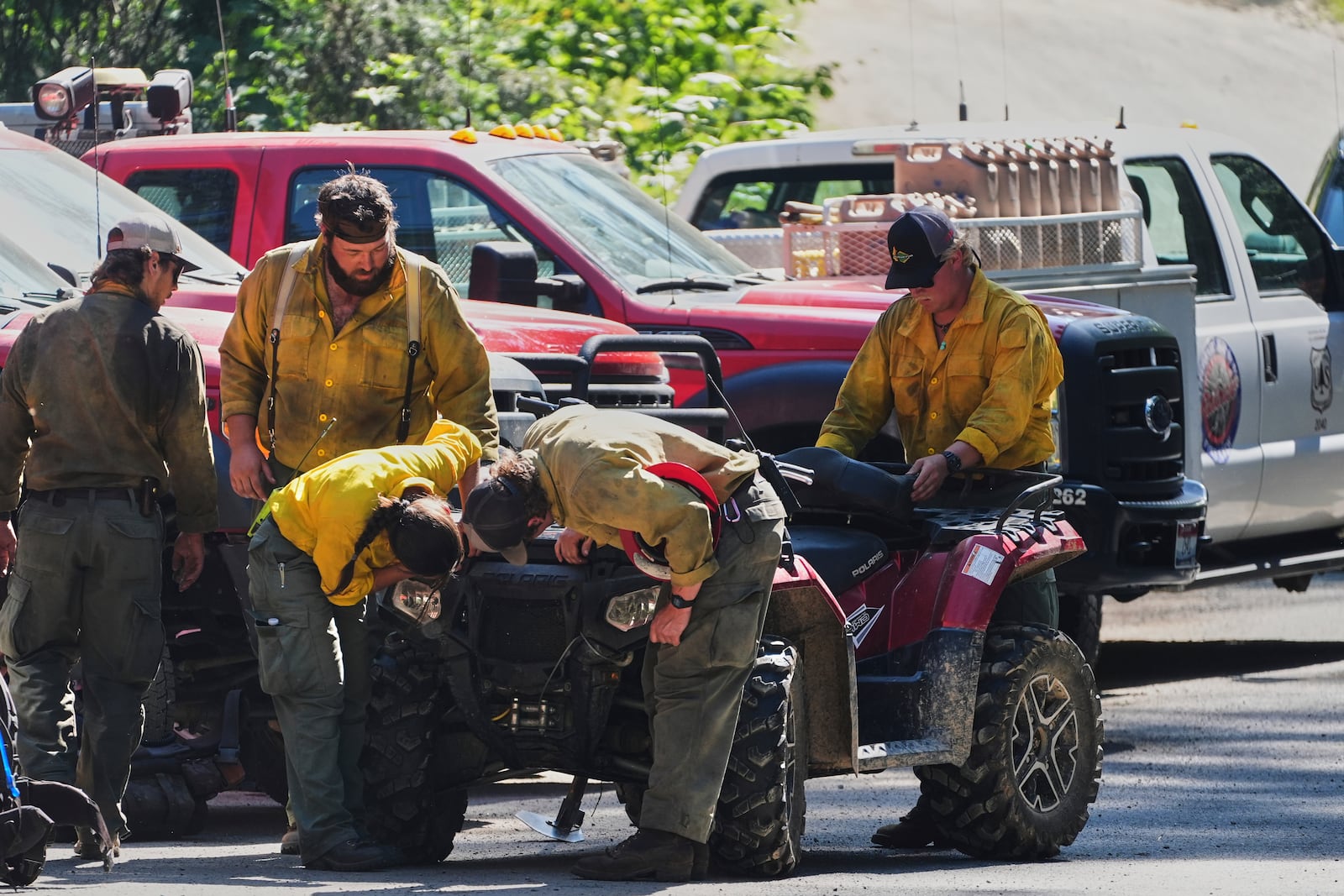 Idaho Department of Lands firefighters inspect an ATV at a staging area near the scene the day after a shooter ambushed and killed multiple firefighters responding to a wildfire at Canfield Mountain Monday, June 30, 2025, in Coeur D'Alene, Idaho. (AP Photo/Lindsey Wasson)
