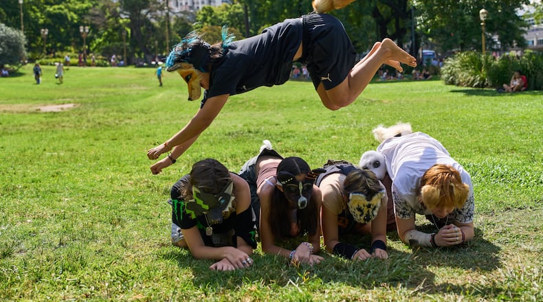 A youth jumps over other therians, people who say they identify as non-human animals, during a gathering in a square in Buenos Aires, Argentina, Sunday, Feb. 22, 2026. (AP Photo/Rodrigo Abd)