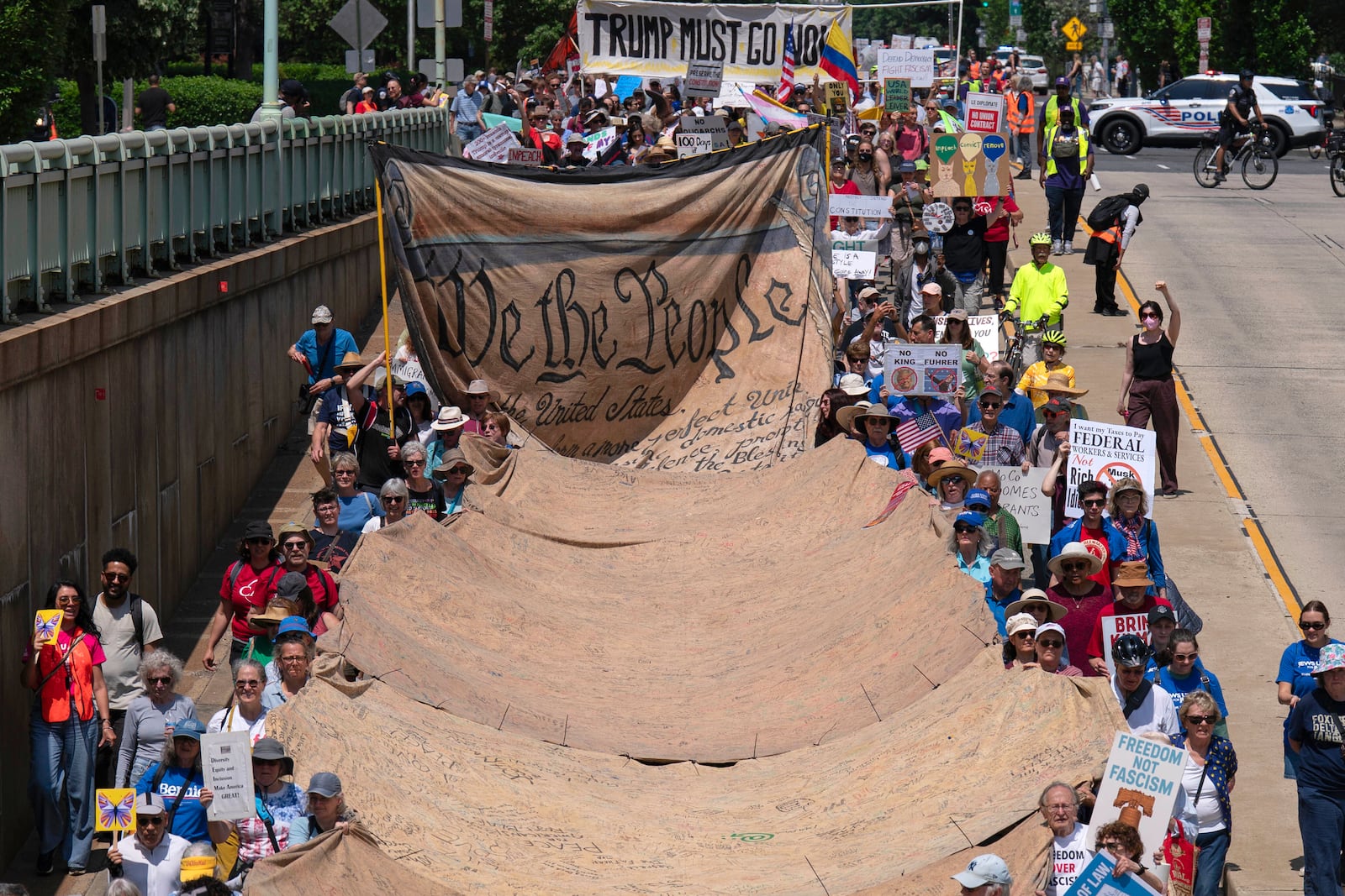Demonstrators holding a banner march to the White House during a May Day protest in Washington, Thursday, May 1, 2025. (AP Photo/Jose Luis Magana)
