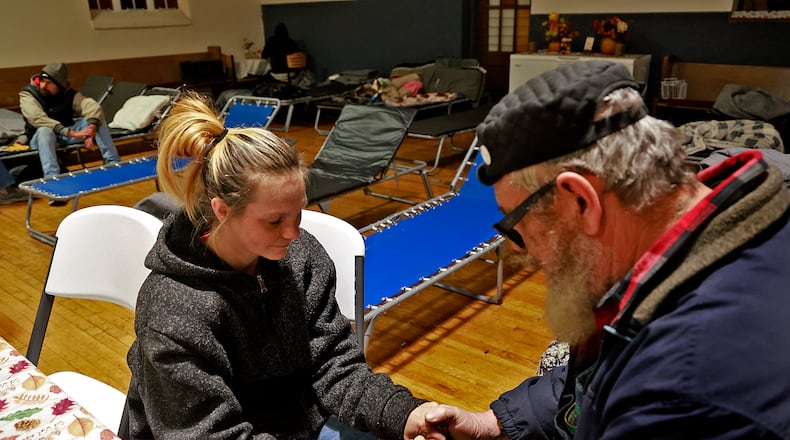 Jazmine Truesdale, who is homeless, prays with Pastor Kenneth "Barron" Seelig Tuesday evening at the warming shelter in the Victory Faith Center gymnasium. Seelig organized the opening of the shelter, with help from community volunteers, as temperatures dropped below freezing outside. The shelter, which also offers a hot meal, opened for the first time on Monday. BILL LACKEY/STAFF