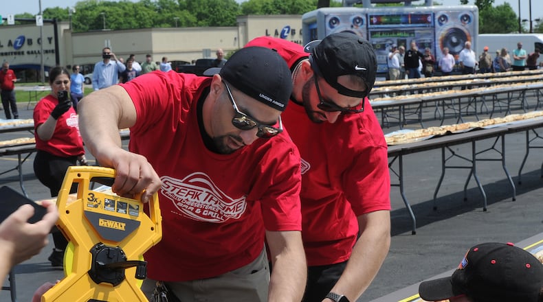 Twin brothers Jordan and Jake Shteiwi, owners of Steak Thyme Bar & Grill at 103 N. Springboro Pike in Miamisburg, celebrated the restaurant's first anniversary Wednesday, May 17, 2023, in a big way by constructing a 650.3-foot-long cheesesteak to beat a world record. MARSHALL GORBY\STAFF