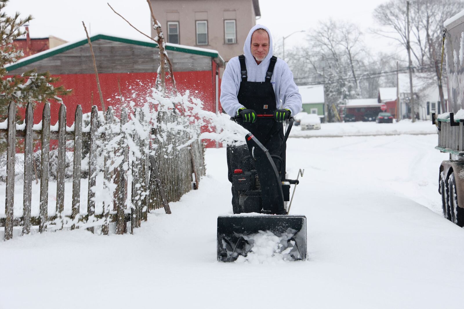 Tony Clawson uses a snow blower to clean off the sidewalk in front of his New Carlisle home Sunday. BILL LACKEY/STAFF