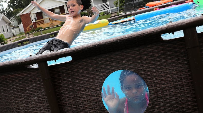 Cash Seagraves and Trinity Anderson found some relief from the heat and humidity Thursday as they played in a backyard pool along James Street in Springfield. BILL LACKEY/STAFF