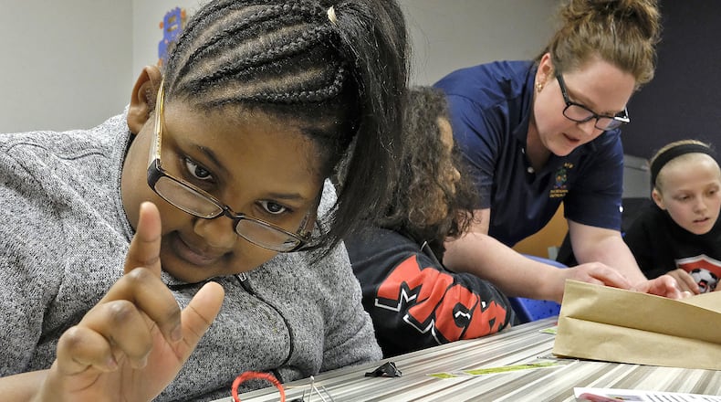 Jadie Welliford plays with the electric motor she made as Dr. Amanda King helps another student during one of the breakout sessions at the Springfield City Schools’ STEM program for girls. Bill Lackey/Staff