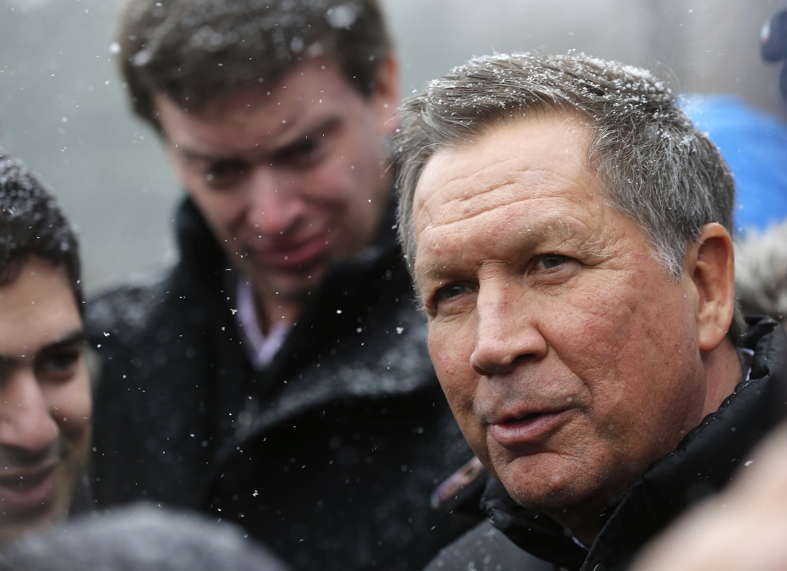 Snow begins to fall as Republican presidential candidate, Ohio Gov. John Kasich talks to reporters after a campaign stop at the public library before next Tuesday's first in the nation presidential primary, Monday, Feb. 8, 2016, in Plaistow, N.H. (AP Photo/Jim Cole)