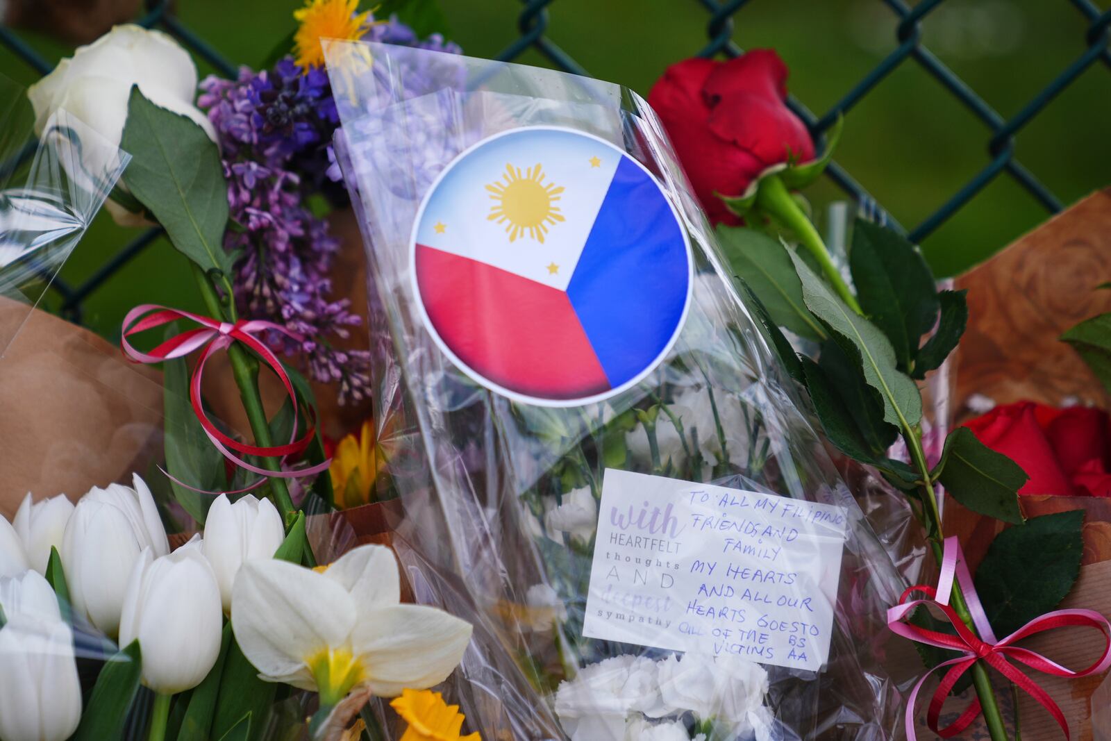 A handwritten note is seen near flowers and the flag of the Philippines at a growing memorial the day after a driver killed multiple people during a Filipino community festival Sunday, April 27, 2025, in Vancouver, British Columbia. (AP Photo/Lindsey Wasson)