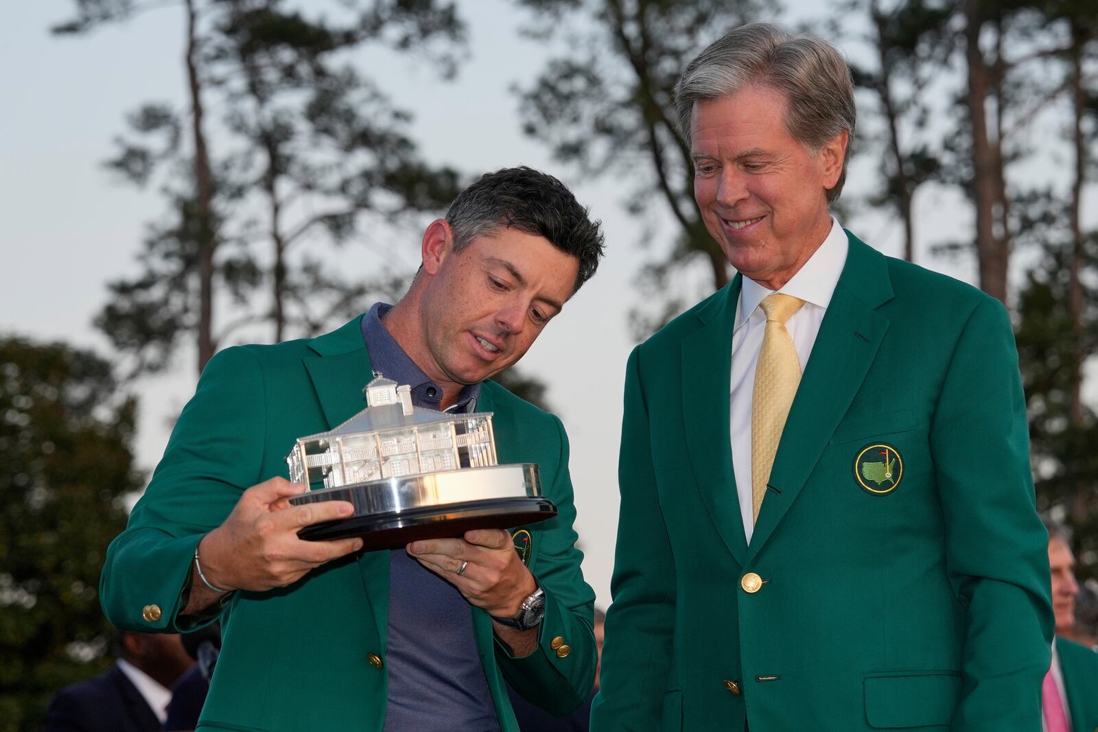 Winner Rory McIlroy, of Northern Ireland, holds the trophy with Masters Chaiman Fred Ridley, right, at the Masters golf tournament, Sunday, April 13, 2025, in Augusta, Ga. (AP Photo/David J. Phillip)