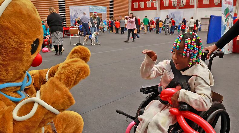 Ilyiah Moore, a guest at the Springfield Rotary Club's Christmas Party for Children with Disabilities, waves to a giant gingerbread man at the party Monday, Dec. 12, 2022. This year marks the Rotary's 100th annual Christmas party. This year's party, held in the Wittenberg University HYPER Center, featured food, games, dancing and of course a present delivered personally from Santa. BILL LACKEY/STAFF