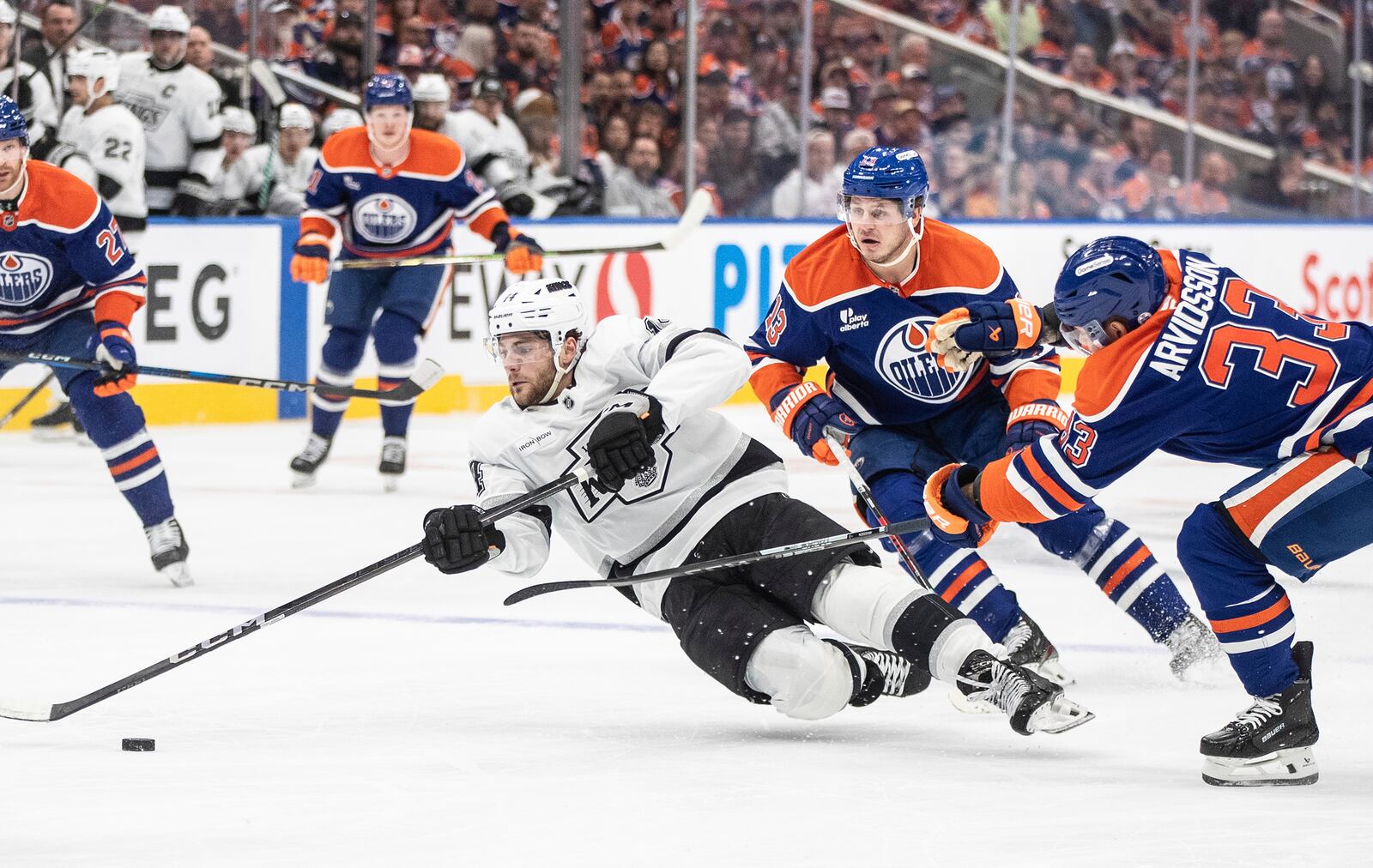 Los Angeles Kings' Alex Laferriere (14) falls while being pressured by Edmonton Oilers' Mattias Janmark (13) and Viktor Arvidsson (33) during the first period of Game 4 in an NHL hockey first-round playoff series in Edmonton, Alberta, Sunday, April 27, 2025. (Jason Franson/The Canadian Press via AP)