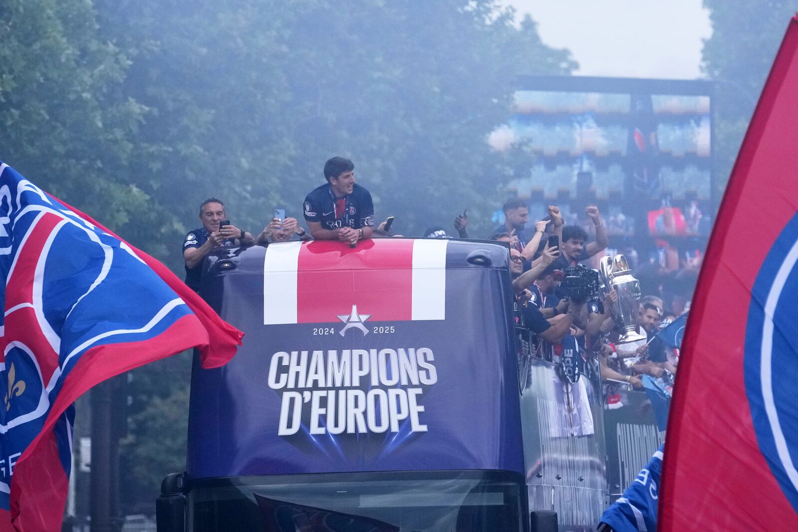 PSG players present the trophy to supporters during a parade on the Champs-Elysees avenue after the team won the Champions League final soccer match between Paris Saint-Germain and Inter Milan Sunday, June 1, 2025 in Paris. (AP Photo/Thibault Camus)