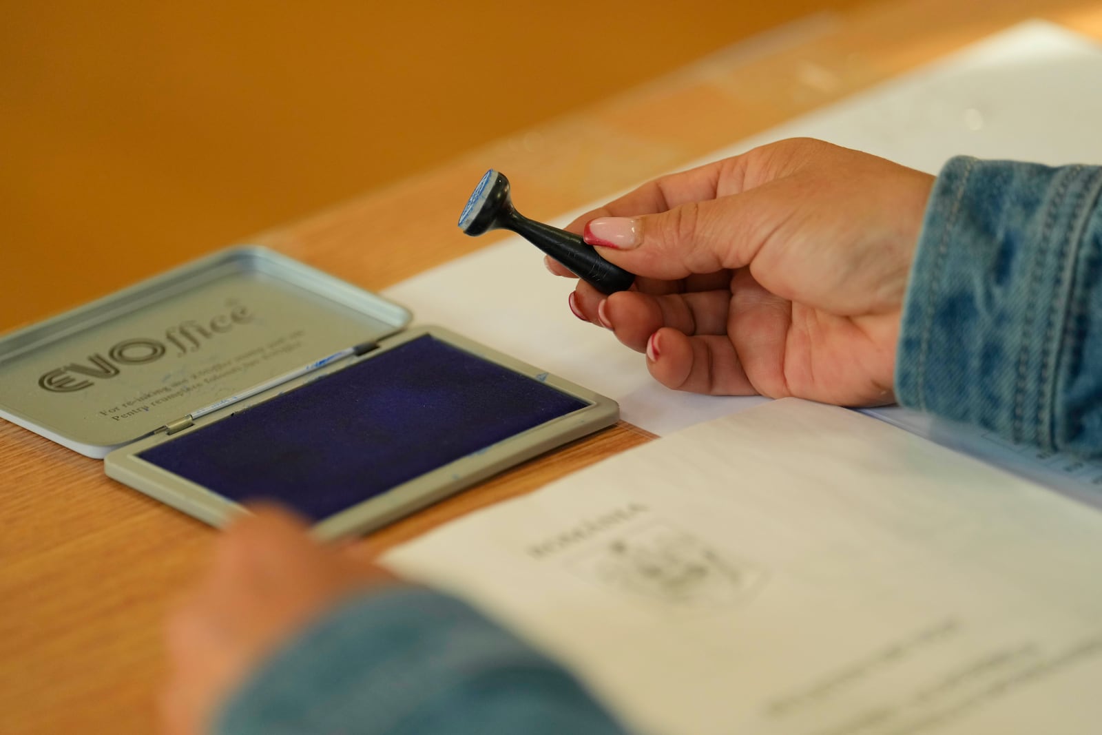 An election official holds a voting stamp during the first round of the presidential election redo in Bucharest, Romania, Sunday, May 4, 2025. (AP Photo/Vadim Ghirda)