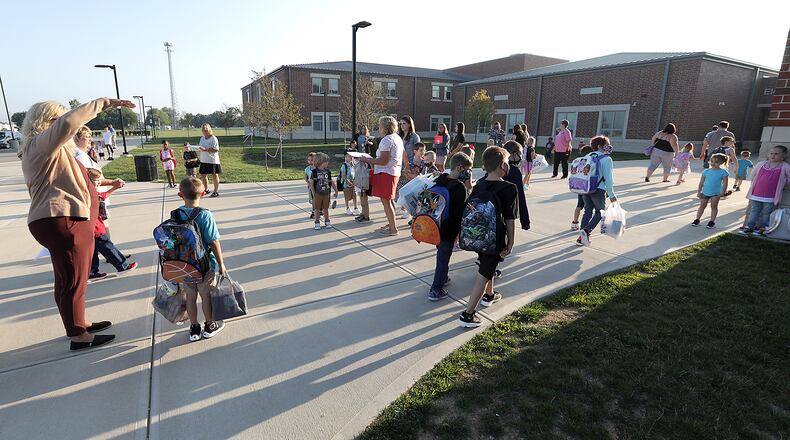 Urbana schools will require masks starting Monday. Here, children walk into Urbana Elementary and Junior High School for the first day of school in August. BILL LACKEY/STAFF