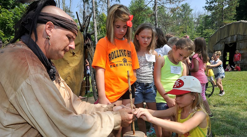 Phil Dzurinda, portraiting one of the Native Americans at the Fair at New Boston, helps a group of students make necklaces Friday during Education Day. Bill Lackey/Staff