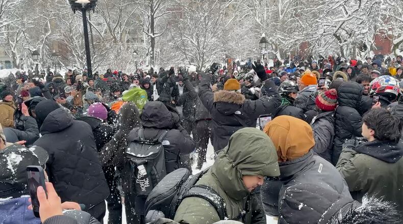 In this photo taken from video, people throw and duck snowballs during a snowball fight at Washington Square Park, Monday, February. 23, 2026 in New York. (AP Photo/David R. Martin)